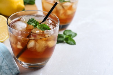 Photo of Delicious iced tea in glass on light table, space for text