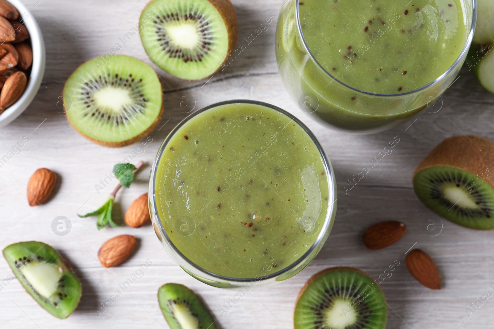 Photo of Delicious kiwi smoothie and ingredients on white wooden table, flat lay
