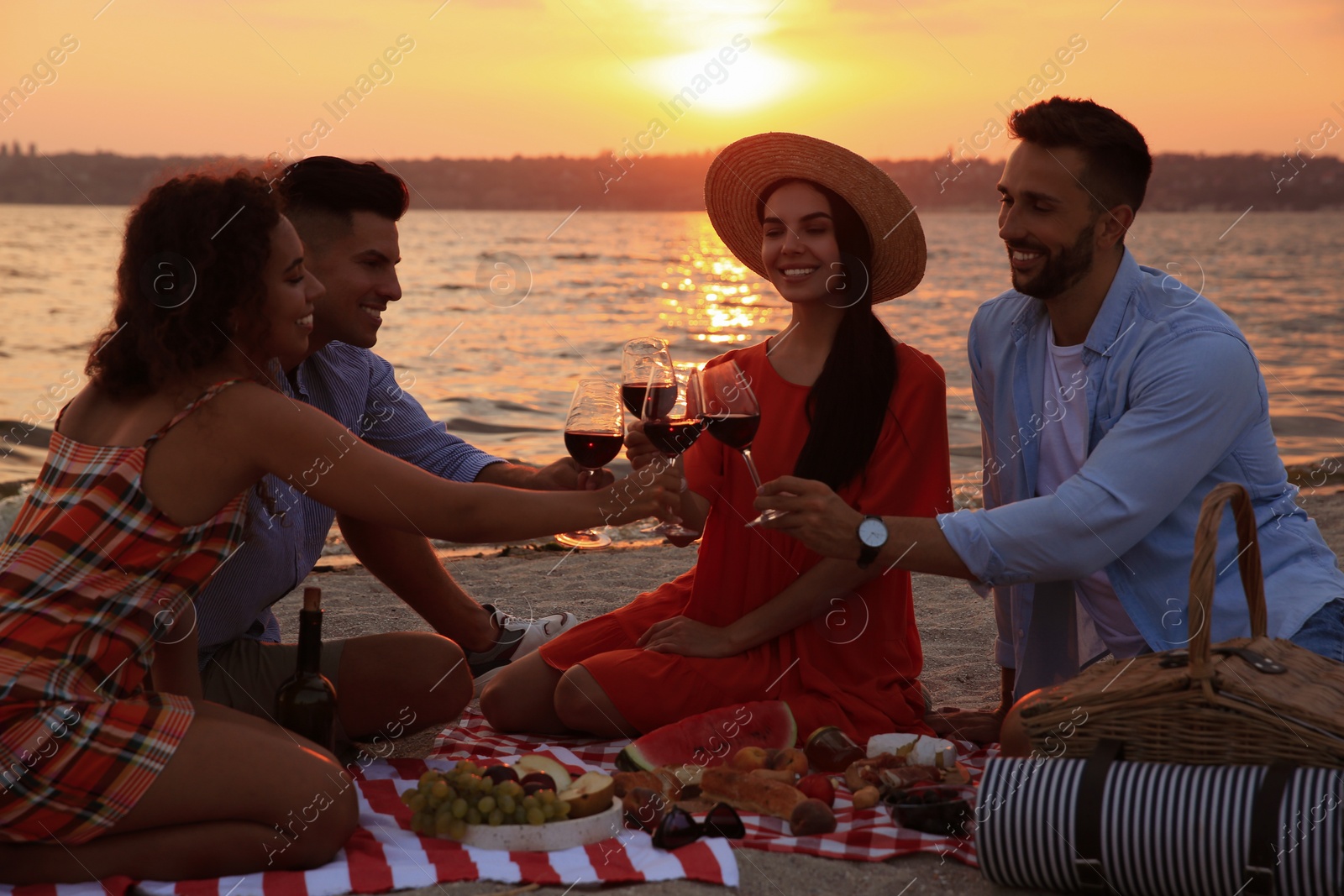 Photo of Group of friends having picnic near river at sunset