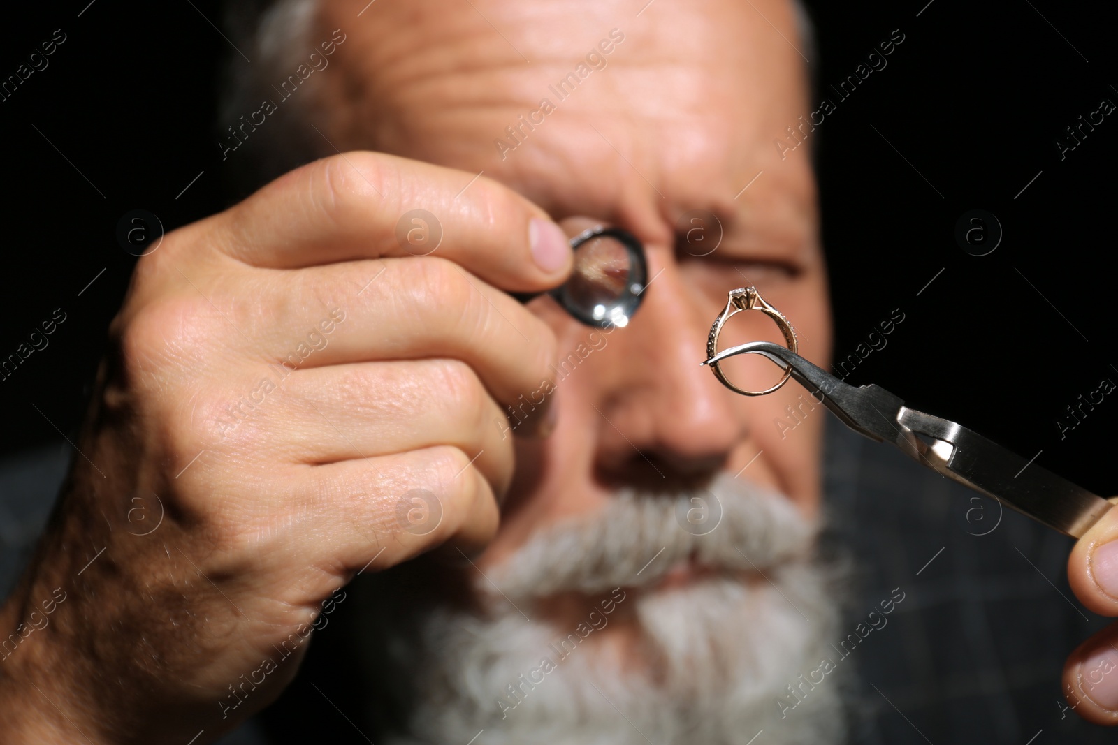 Photo of Male jeweler evaluating diamond ring in workshop, closeup view