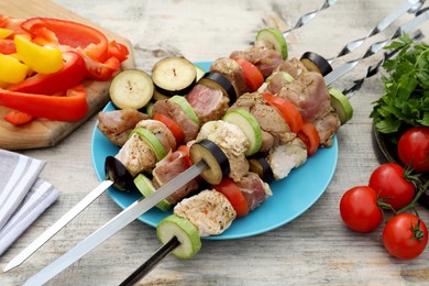 Metal skewers with raw marinated meat and vegetables on wooden table