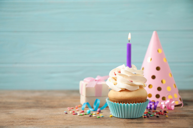 Photo of Composition with birthday cupcake on wooden table against light blue background. Space for text