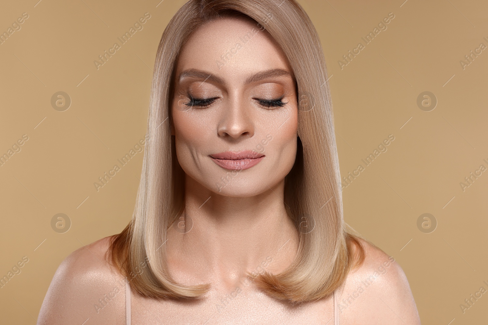 Image of Portrait of attractive woman with blonde hair on dark beige background