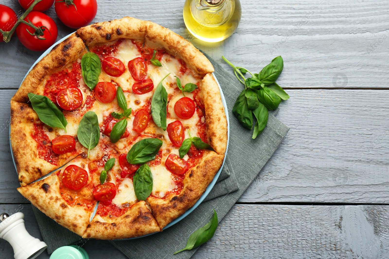 Photo of Delicious Margherita pizza and ingredients on gray wooden table, flat lay. Space for text