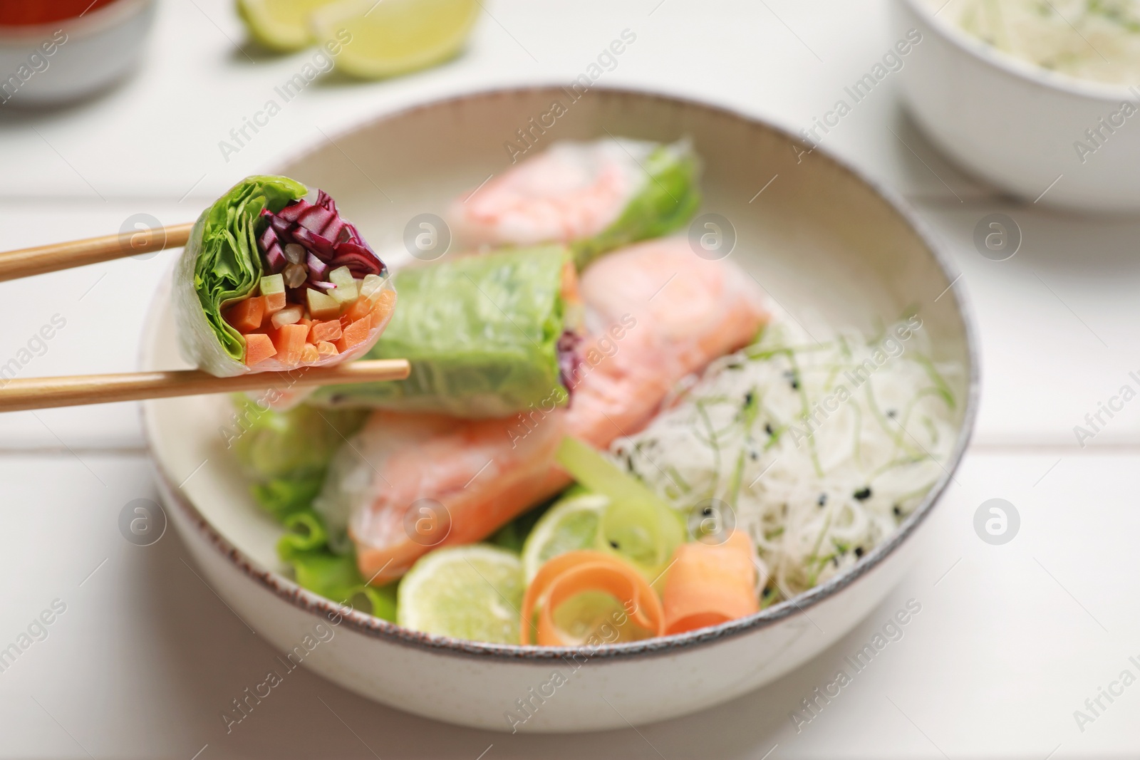 Photo of Delicious spring rolls wrapped in rice paper on white wooden table, closeup