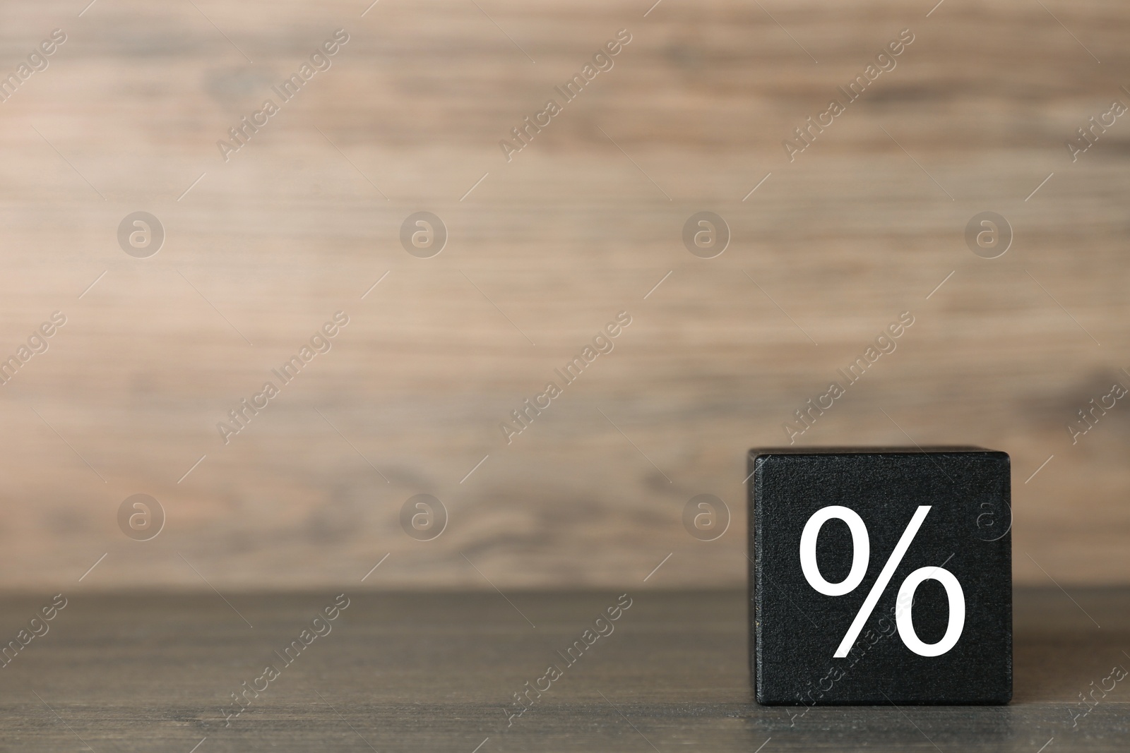 Photo of Black cube with percent sign on wooden table, space for text