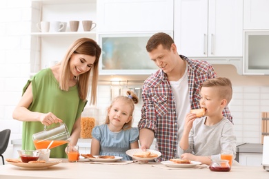 Photo of Parents and cute little children having breakfast with tasty toasted bread at table in kitchen