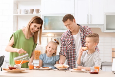 Parents and cute little children having breakfast with tasty toasted bread at table in kitchen