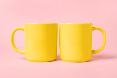 Two yellow ceramic mugs on pink background