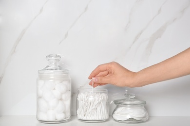 Young woman taking cotton swab from jar indoors, closeup