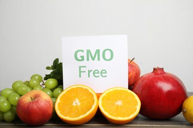Photo of Tasty fresh GMO free products and paper card on wooden table against light background