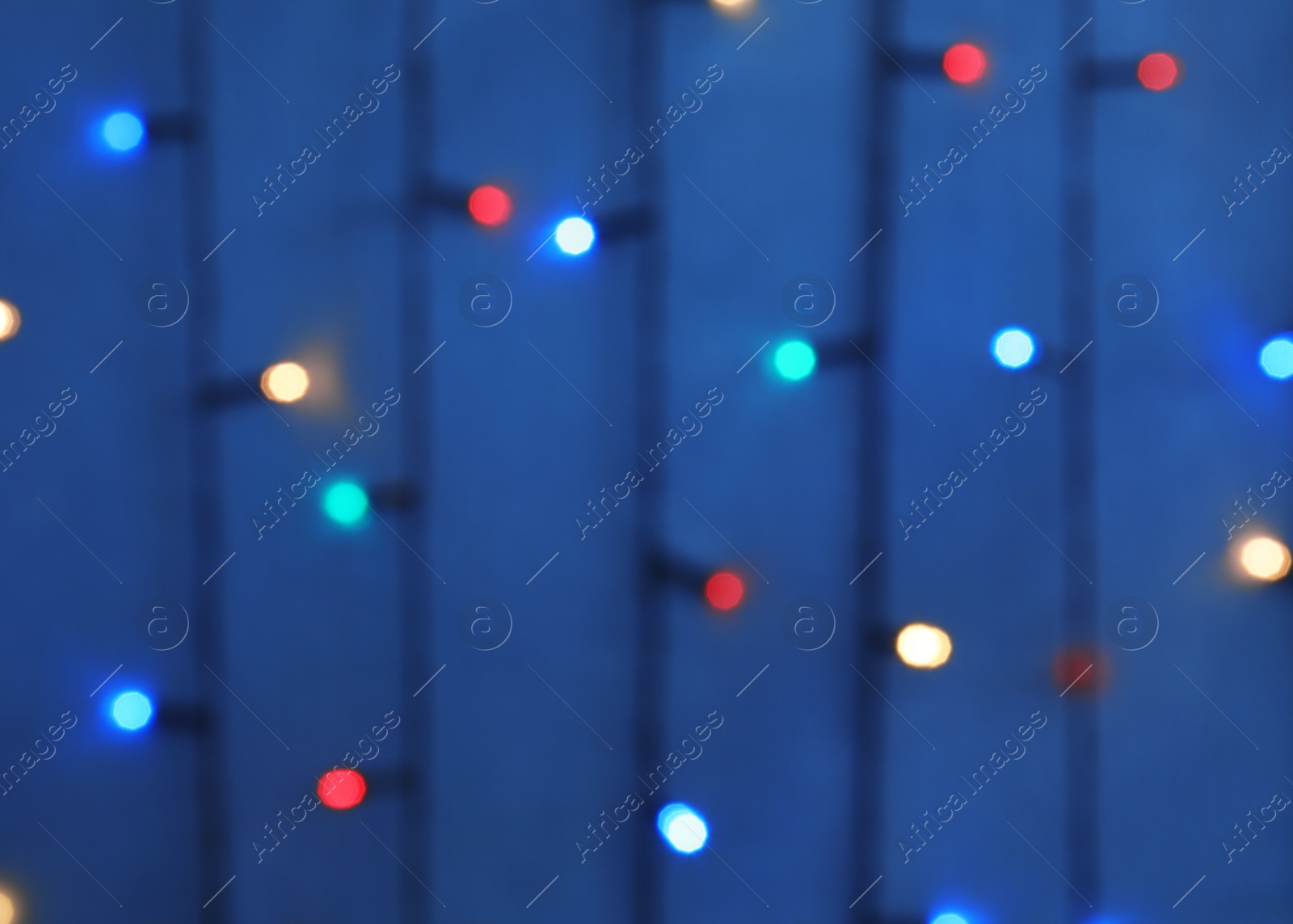 Photo of Blurred view of Christmas lights on color background