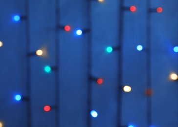 Blurred view of Christmas lights on color background