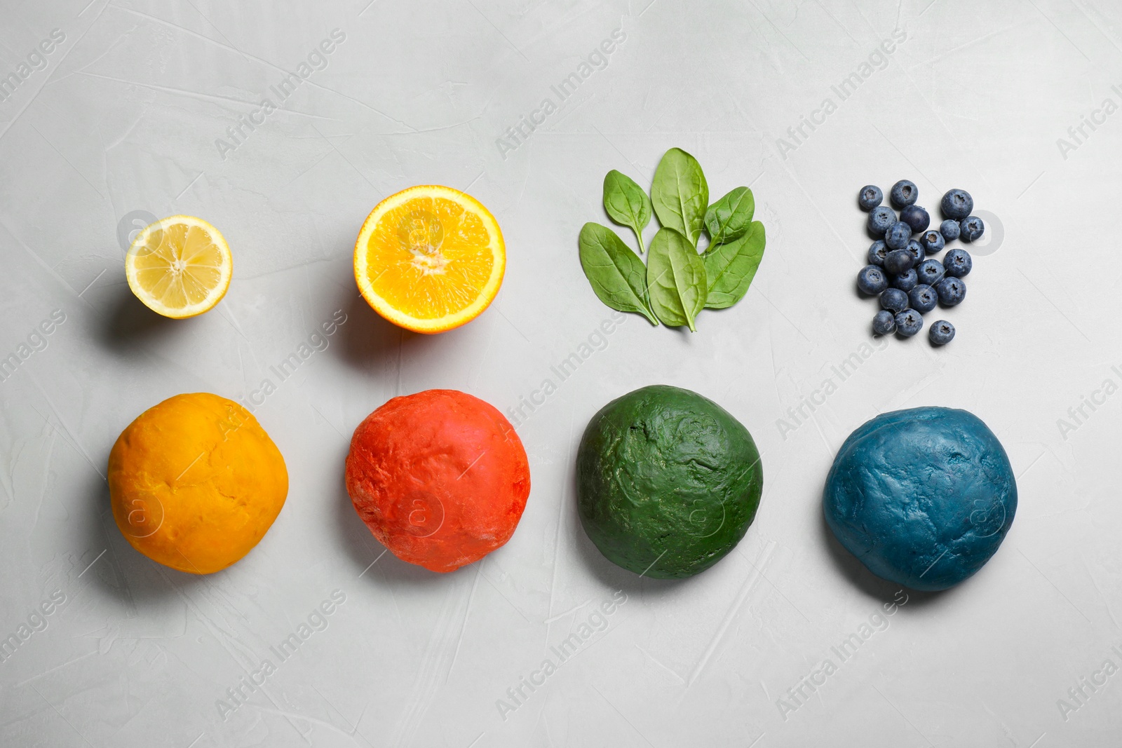 Photo of Dough painted with natural food colorings and ingredients on light grey table, flat lay