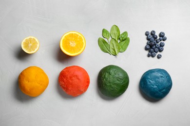 Photo of Dough painted with natural food colorings and ingredients on light grey table, flat lay