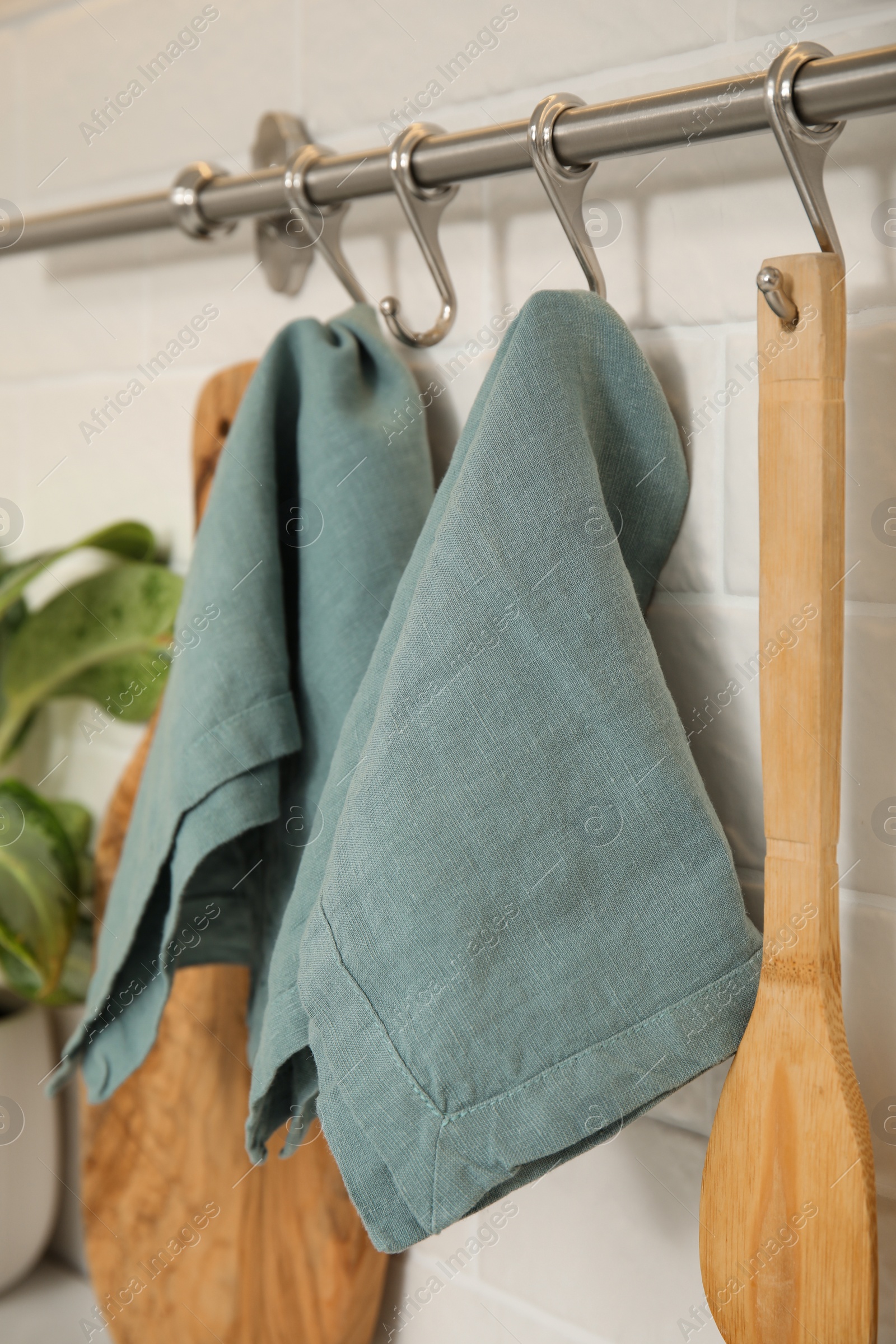 Photo of Clean towels and utensils hanging on rack in kitchen