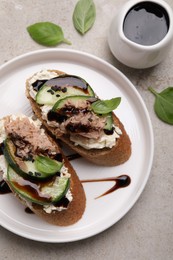 Delicious bruschettas with balsamic vinegar and toppings on light textured table, flat lay