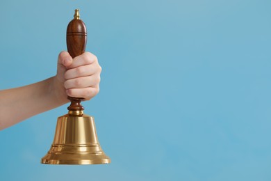 Photo of Pupil with school bell on light blue background, closeup. Space for text