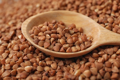 Pile of uncooked buckwheat with spoon, closeup