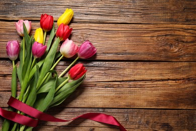 Beautiful colorful tulip flowers and ribbon on wooden table, flat lay. Space for text