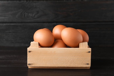 Wooden crate full of fresh eggs on dark background