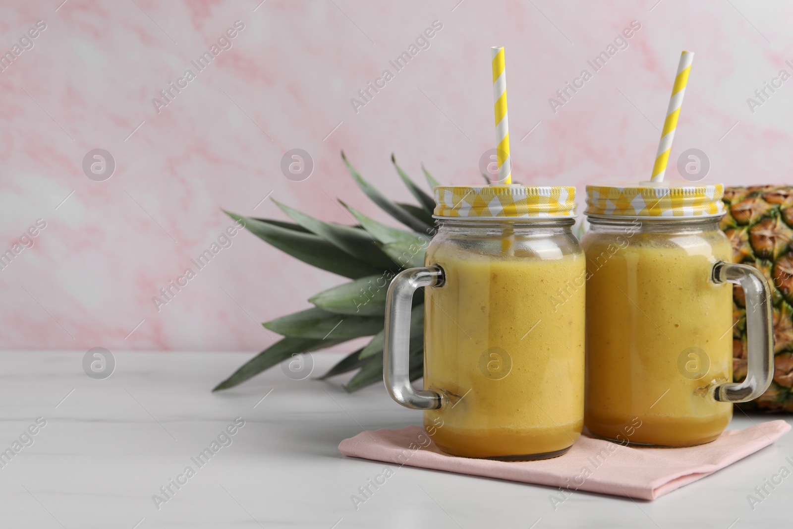 Photo of Tasty pineapple smoothie and fruit on white marble table, closeup. Space for text