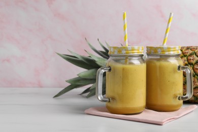 Tasty pineapple smoothie and fruit on white marble table, closeup. Space for text