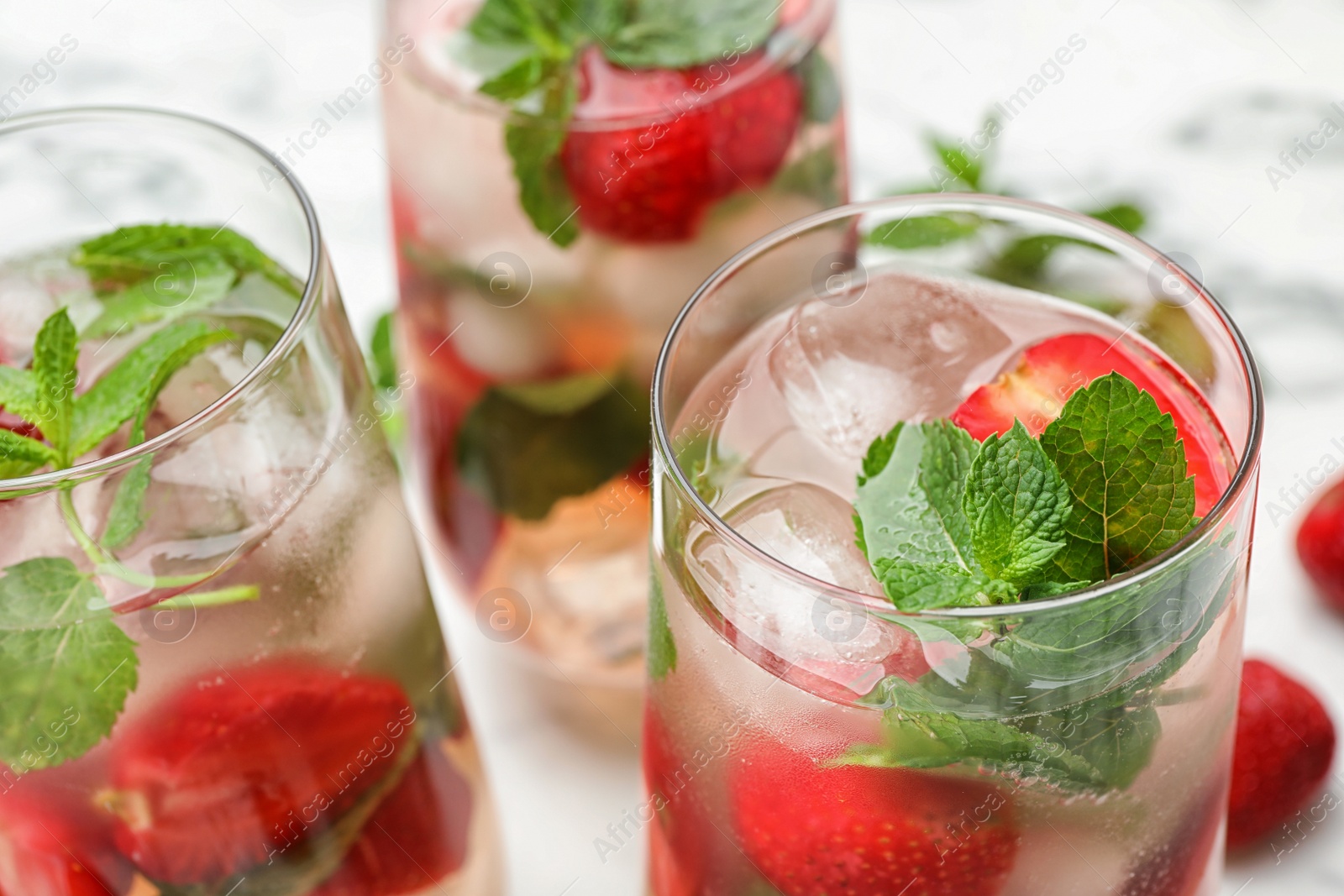 Photo of Glasses of refreshing drink with strawberry and mint on table, closeup view