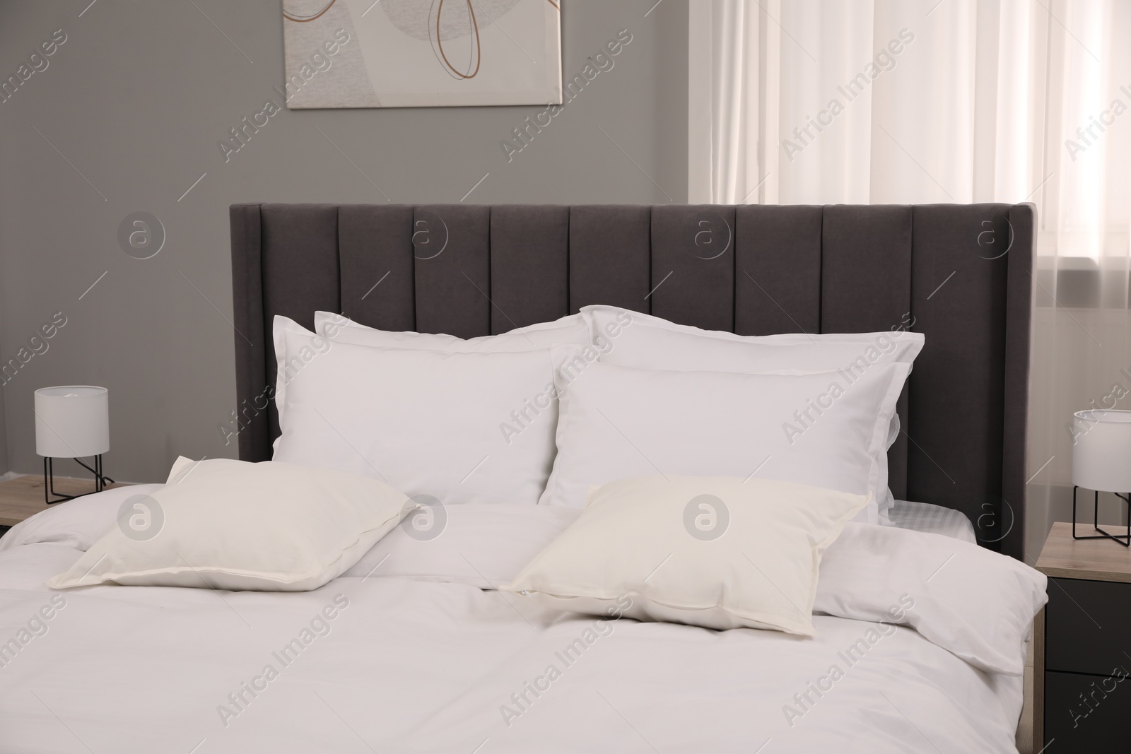 Photo of Many soft white pillows and duvet on bed indoors