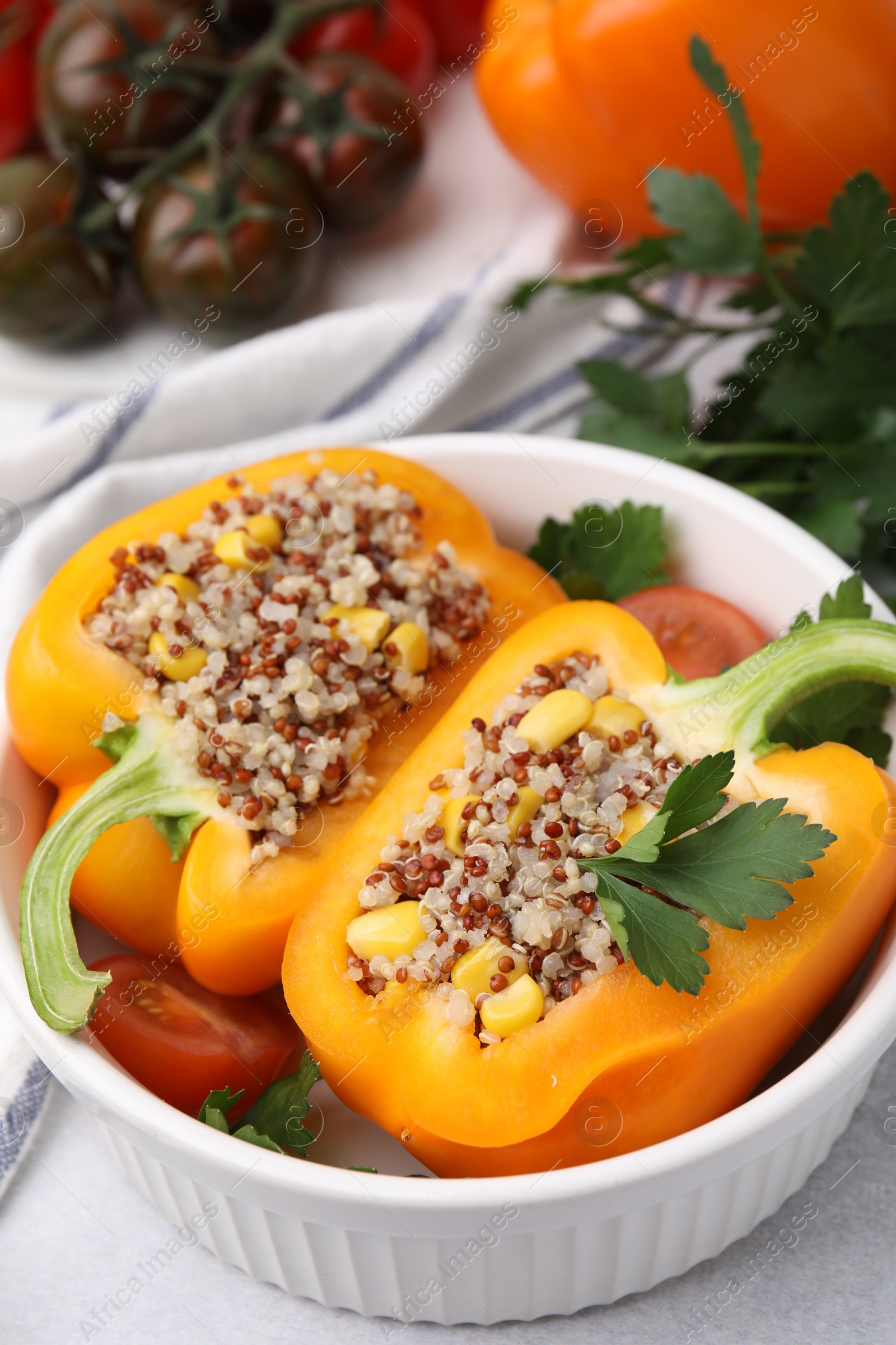 Photo of Quinoa stuffed bell pepper and parsley in bowl on light table, closeup