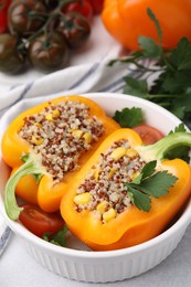 Photo of Quinoa stuffed bell pepper and parsley in bowl on light table, closeup