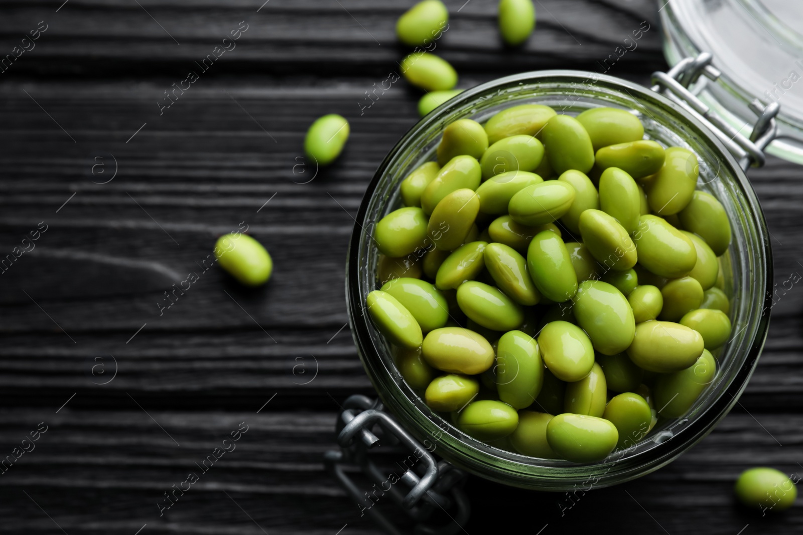 Photo of Jar of edamame beans on black wooden table, flat lay. Space for text