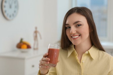 Photo of Beautiful young woman with delicious smoothie at home. Space for text