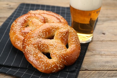 Photo of Tasty pretzels and glass of beer on wooden table, closeup
