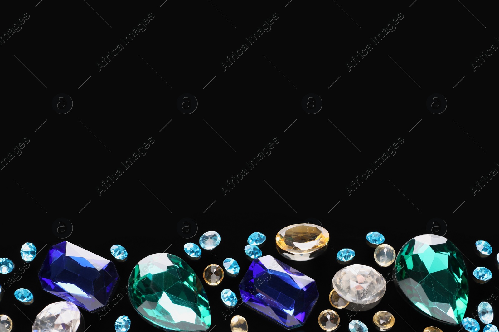 Photo of Different beautiful gemstones for jewelry on black background, flat lay. Space for text