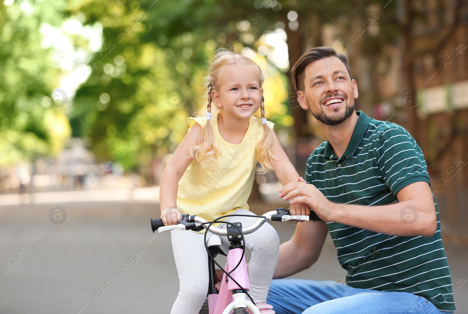 Photo of Father teaching daughter to ride bicycle on street