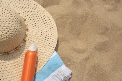 Sunscreen, hat and towel on sand, above view with space for text. Sun protection care