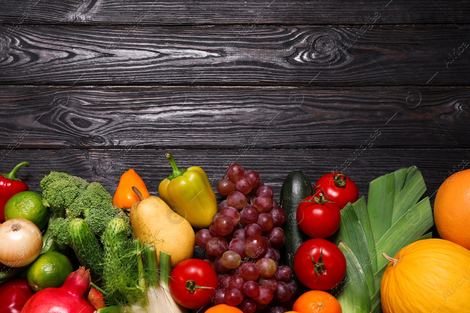 Photo of Assortment of fresh organic fruits and vegetables on black wooden table, flat lay. Space for text