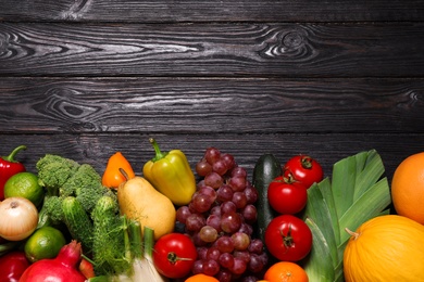 Photo of Assortment of fresh organic fruits and vegetables on black wooden table, flat lay. Space for text