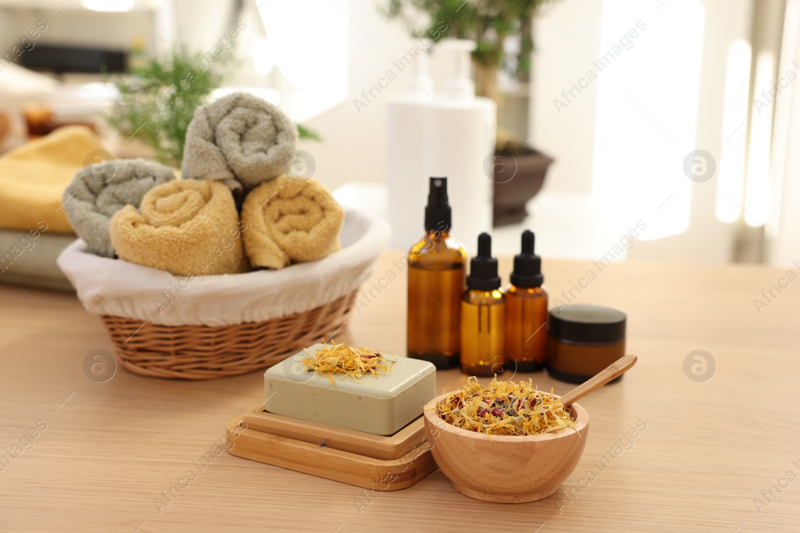 Photo of Soap bar, dry flowers, bottles of essential oils, jar with cream and towels on wooden table indoors. Spa time