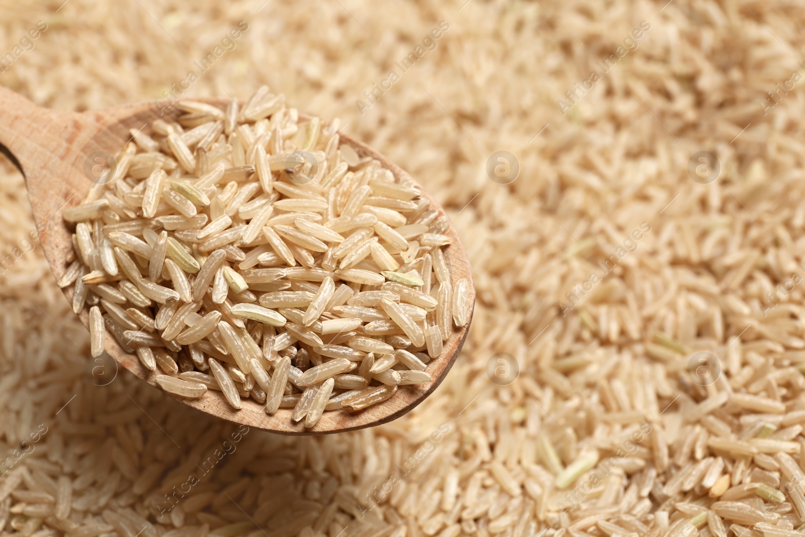 Photo of Brown rice in wooden spoon, closeup view