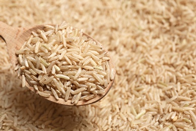 Photo of Brown rice in wooden spoon, closeup view