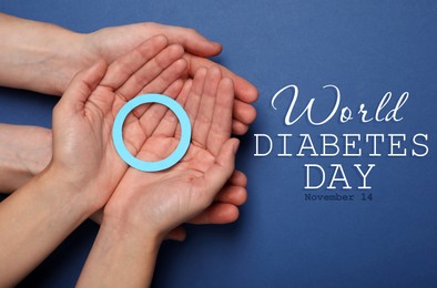Image of People showing blue paper circle as World Diabetes Day symbol on color background, top view 
