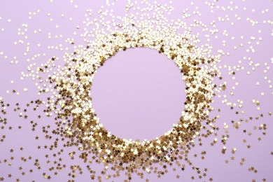 Frame of confetti stars on violet background, flat lay with space for text. Christmas celebration