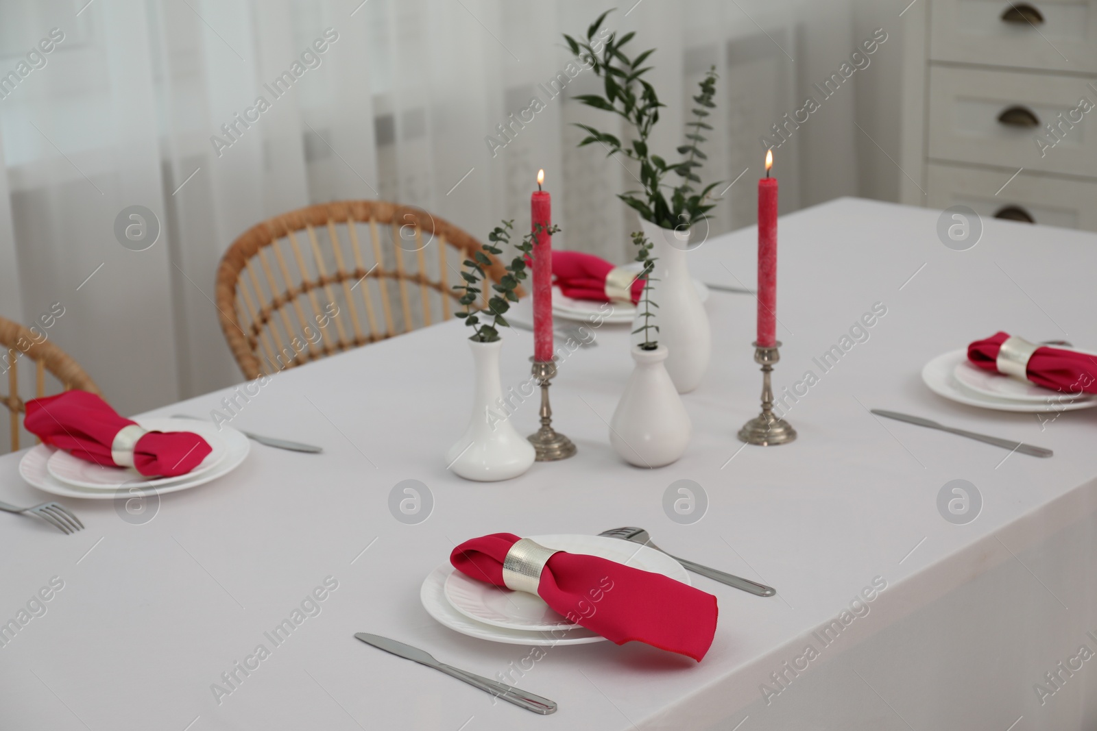 Photo of Beautiful table setting with green branches in vases and burning candles indoors. Stylish dining room