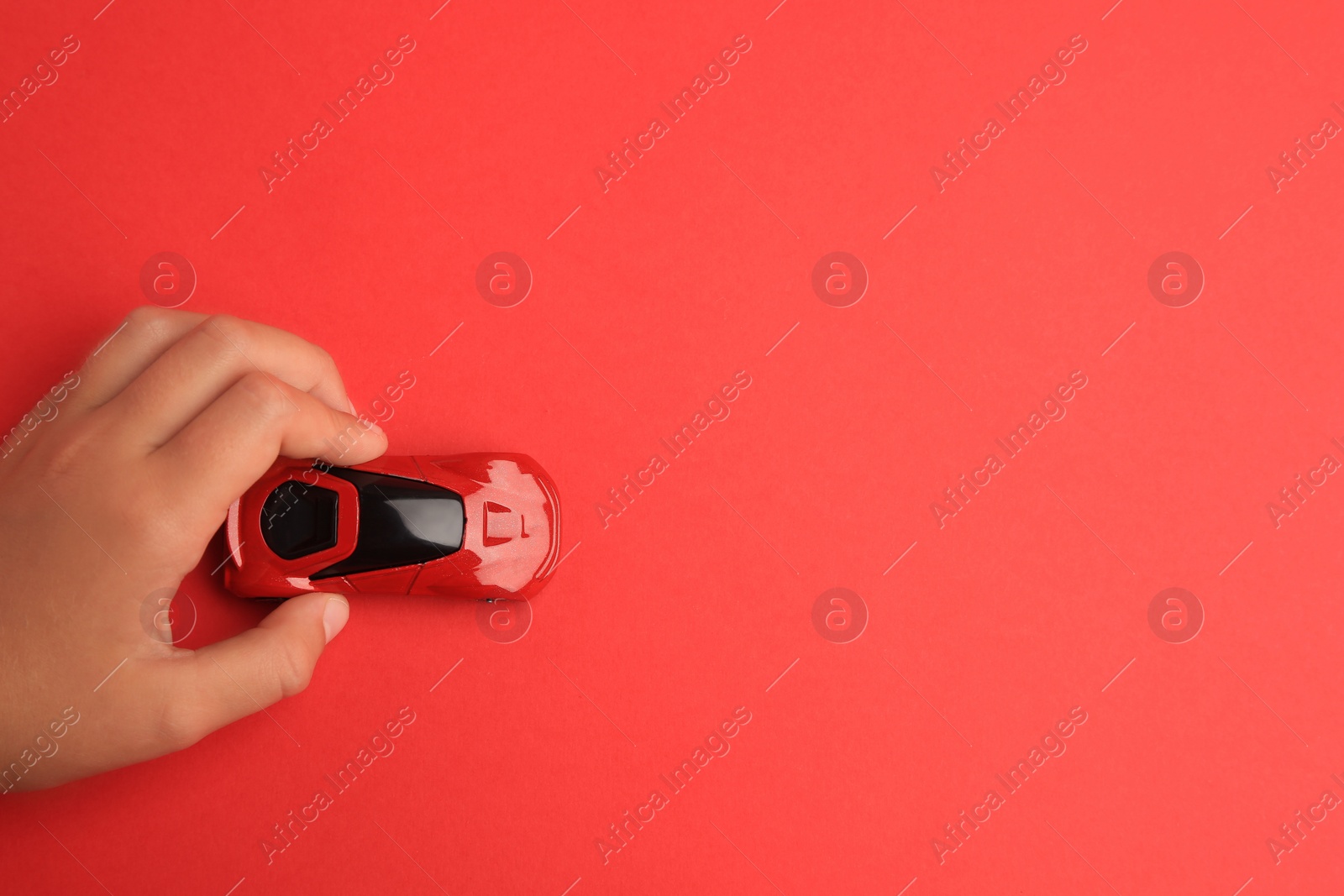 Photo of Child playing with toy car on red background, top view. Space for text