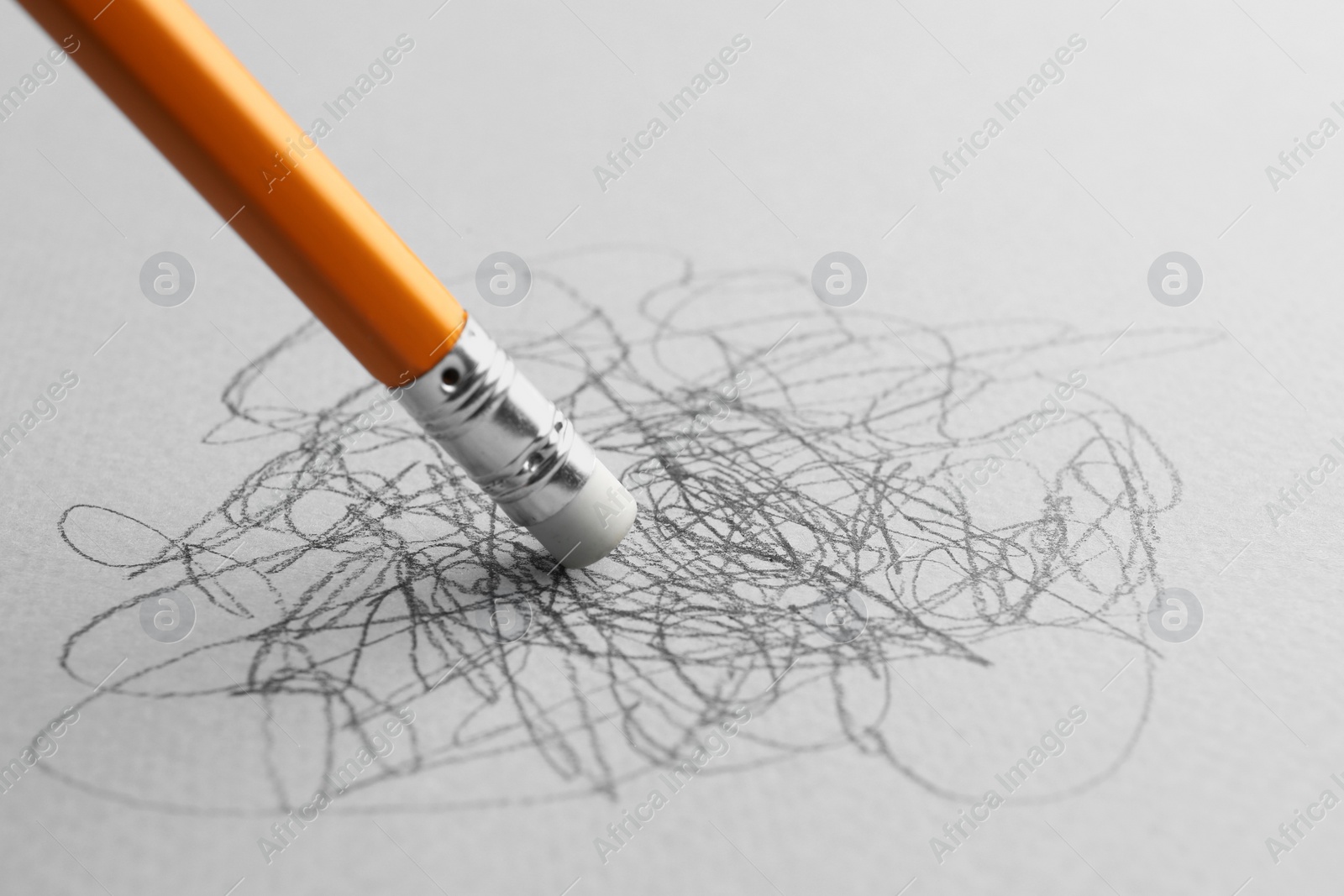 Photo of Erasing scribbles with graphite pencil on white background, closeup. Space for text