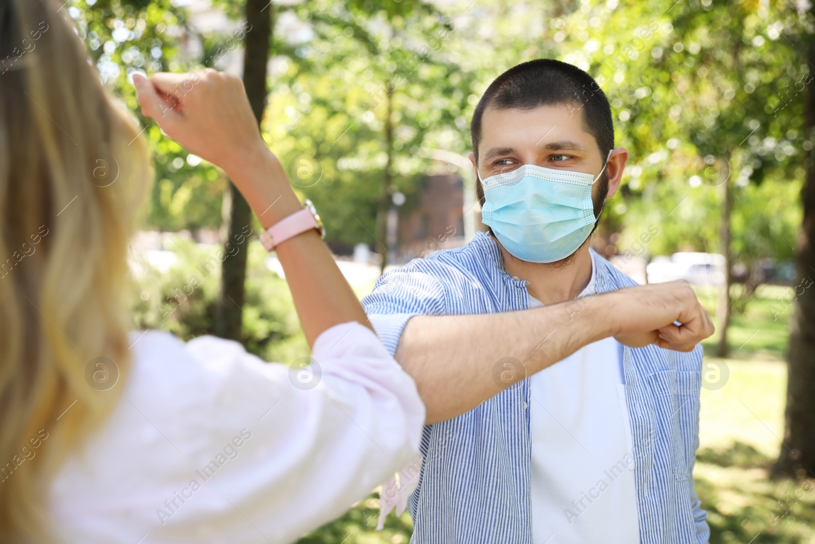 Photo of Man and woman bumping elbows to say hello outdoors. Keeping social distance during coronavirus pandemic