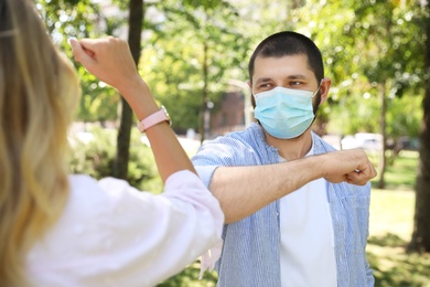 Man and woman bumping elbows to say hello outdoors. Keeping social distance during coronavirus pandemic