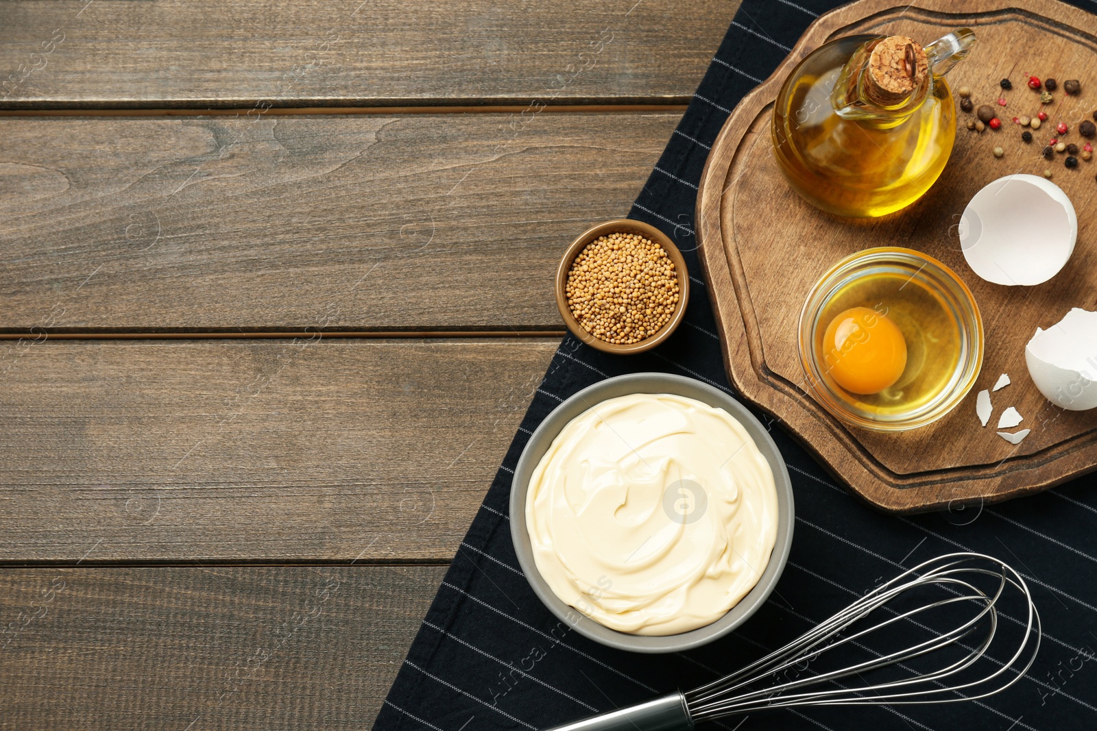 Photo of Bowl with fresh mayonnaise and ingredients on wooden table, top view. Space for text